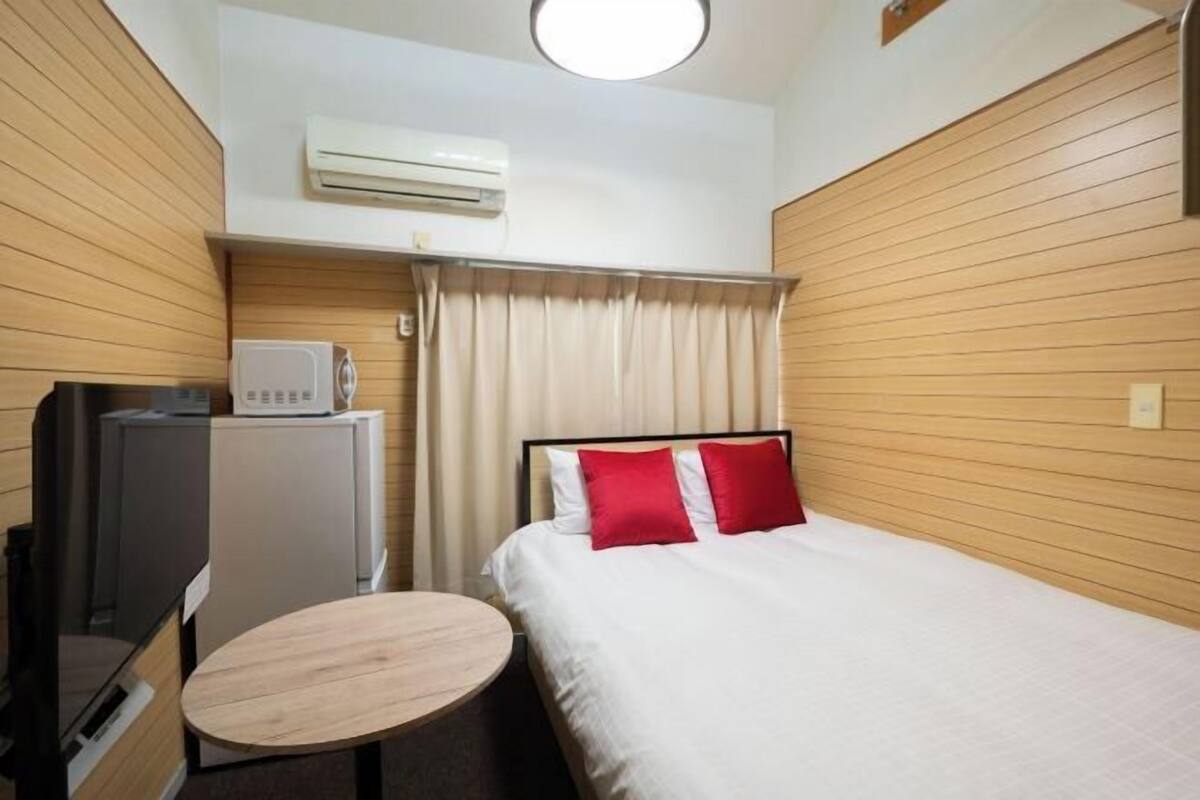 Une chambre d’hôtel équipée d’un lit, d’une petite table, d’un téléviseur et d’un appareil de climatisation.