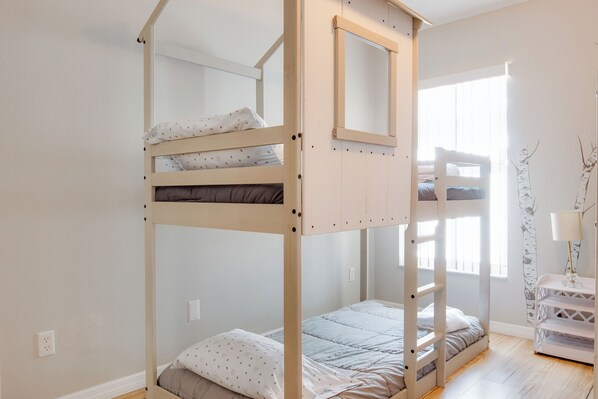 A bunk bed with a wooden frame, a small window, and a white wall. - Magic Retreat Orlando (Davenport)