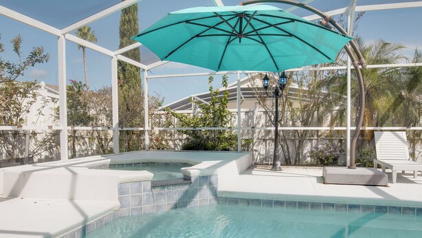 A swimming pool with a turquoise umbrella, white tiled steps, and a white lounge chair. - Magic Retreat Orlando (Davenport)