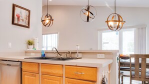 A modern kitchen with wooden cabinets, a built-in dishwasher, and pendant lighting. - Magic Retreat Orlando (Davenport)