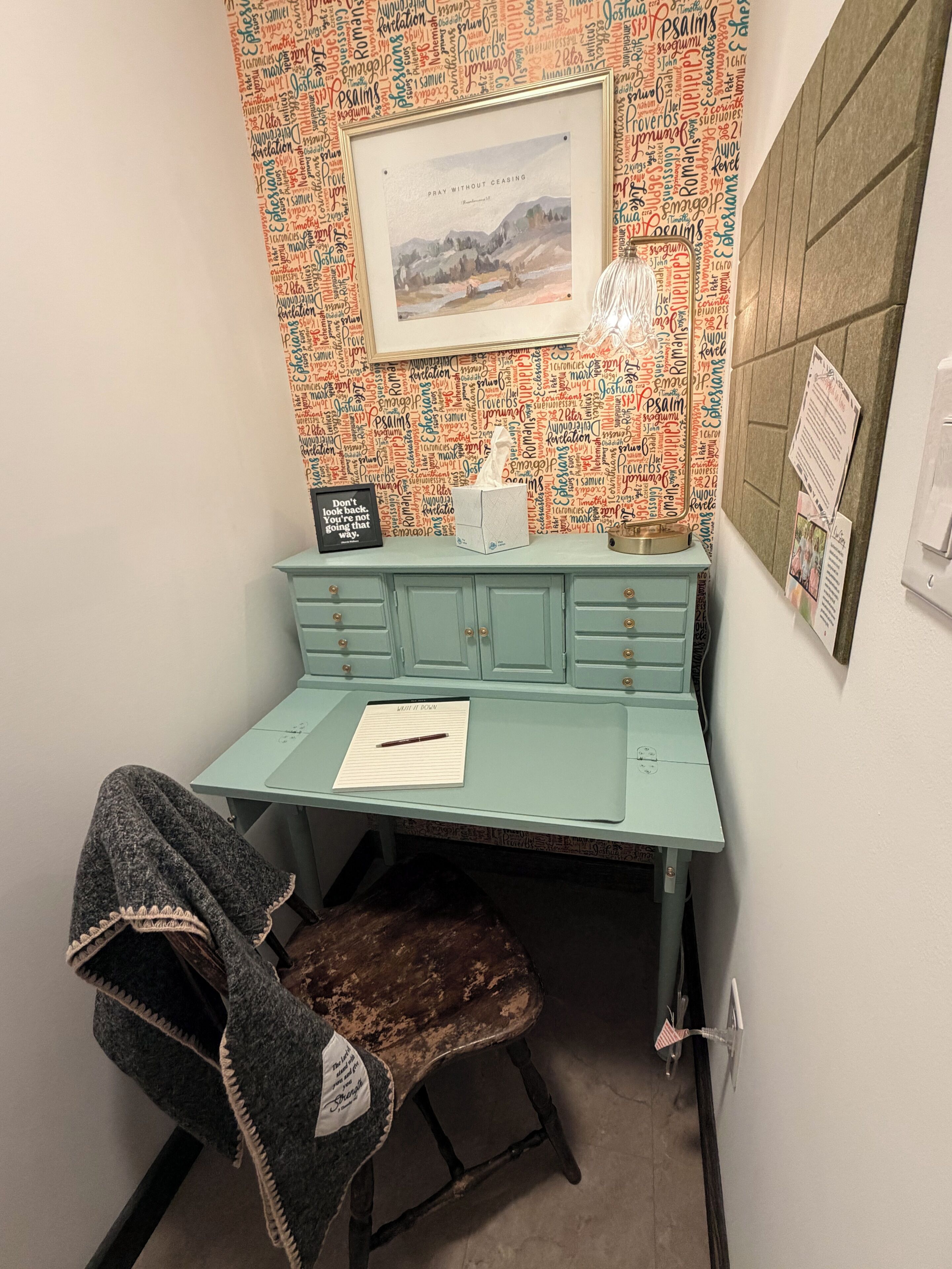 A corner desk with a framed picture, a tissue box, and a sign on the wall.