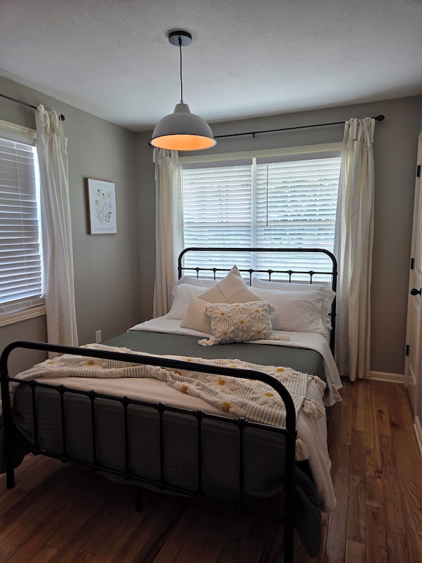 A neatly arranged bedroom with a bed, a hanging light fixture, and a window with blinds. - Quite, cozy farmhouse in the country near Albertville, (Albertville)