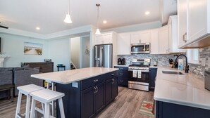 Una cocina moderna con una isla central, electrodomésticos de acero inoxidable y muebles blancos.
