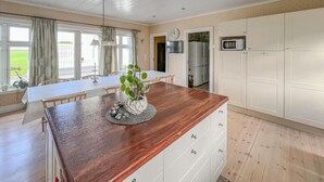 Une cuisine moderne avec des plans de travail en bois, des armoires blanches et un coin repas comprenant une table et des chaises.