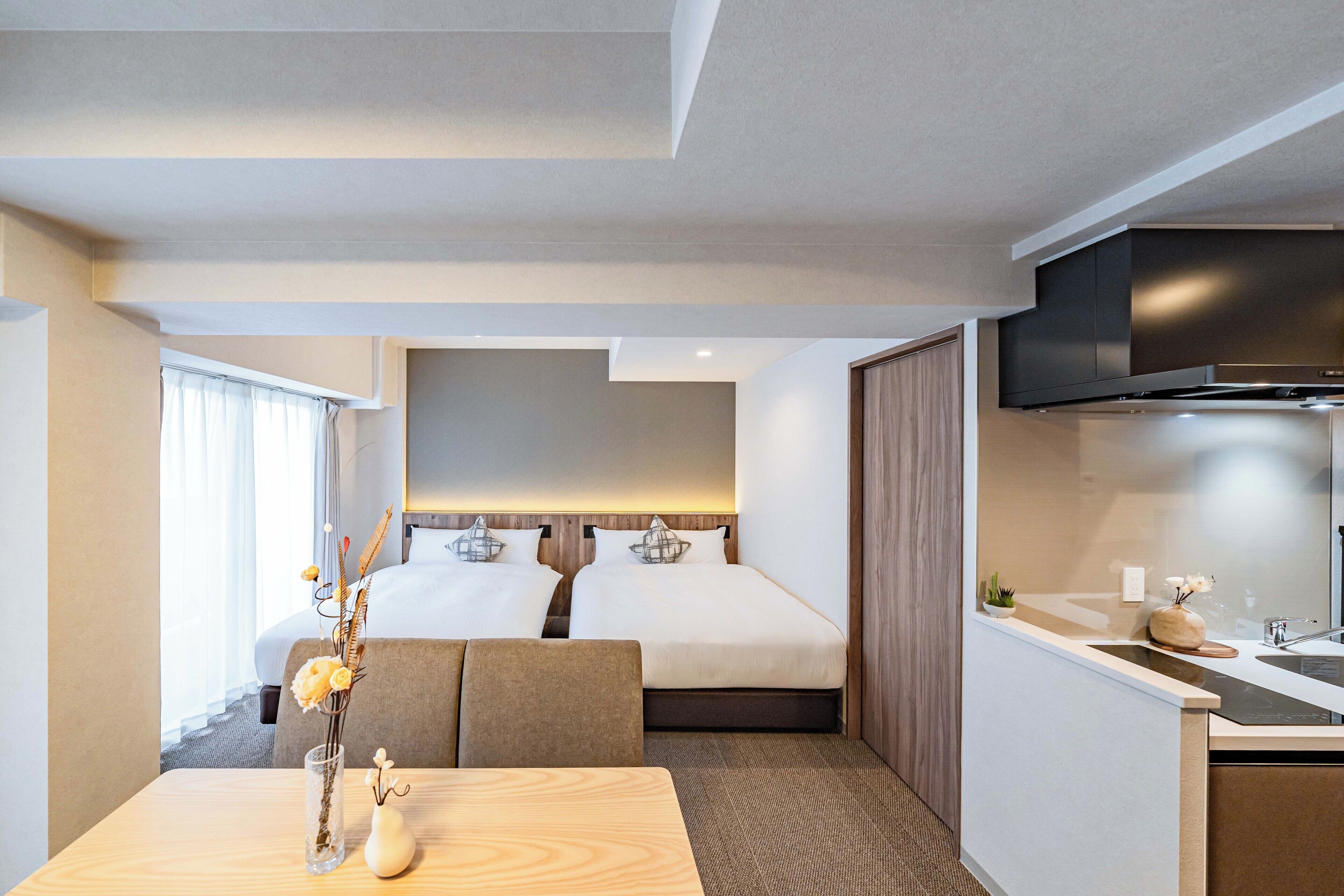 A hotel room with a bed, a small sitting area, a kitchenette, and a TV.