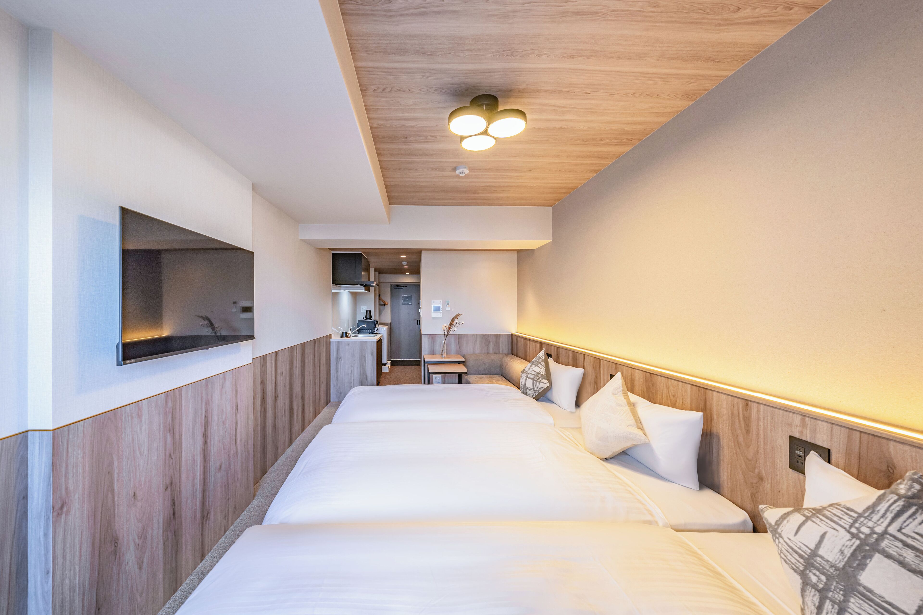 A hotel room with a large bed, a small desk, and a TV mounted on the wall.