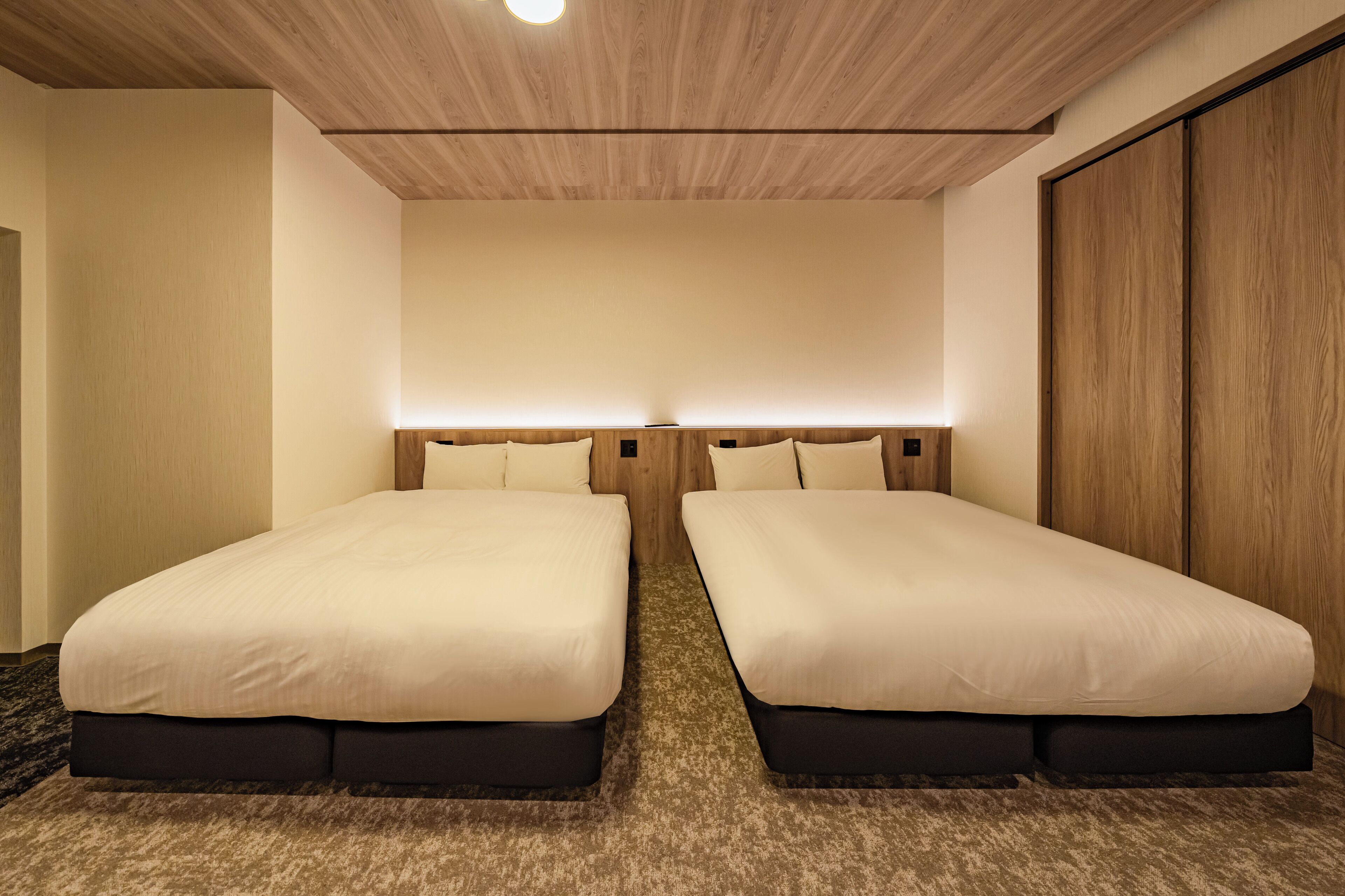 Une chambre d’hôtel avec deux lits simples, un plafond en bois et une grande armoire.