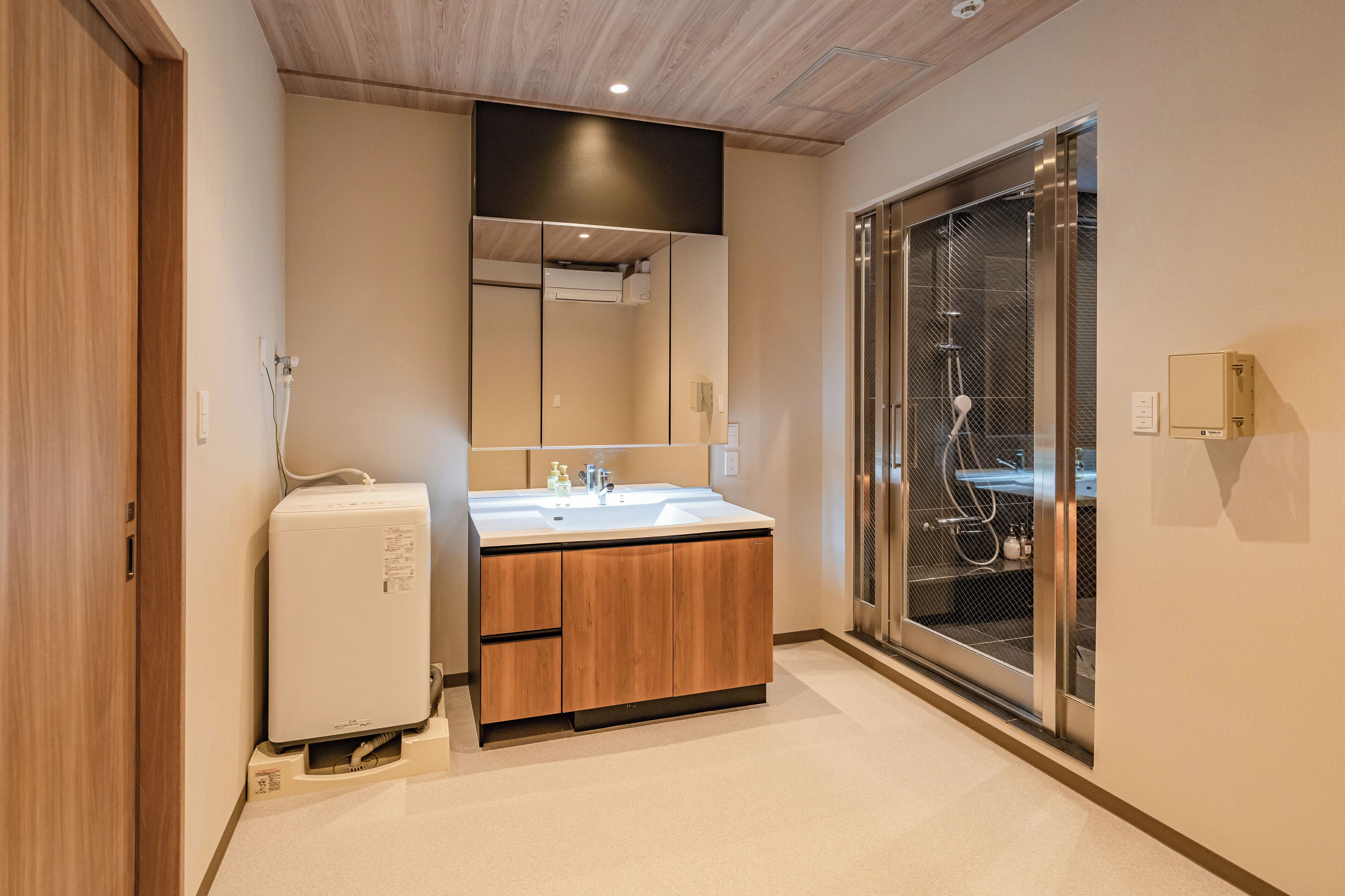 Un baño moderno con tocador de madera, un espejo grande y cabina de ducha de vidrio.