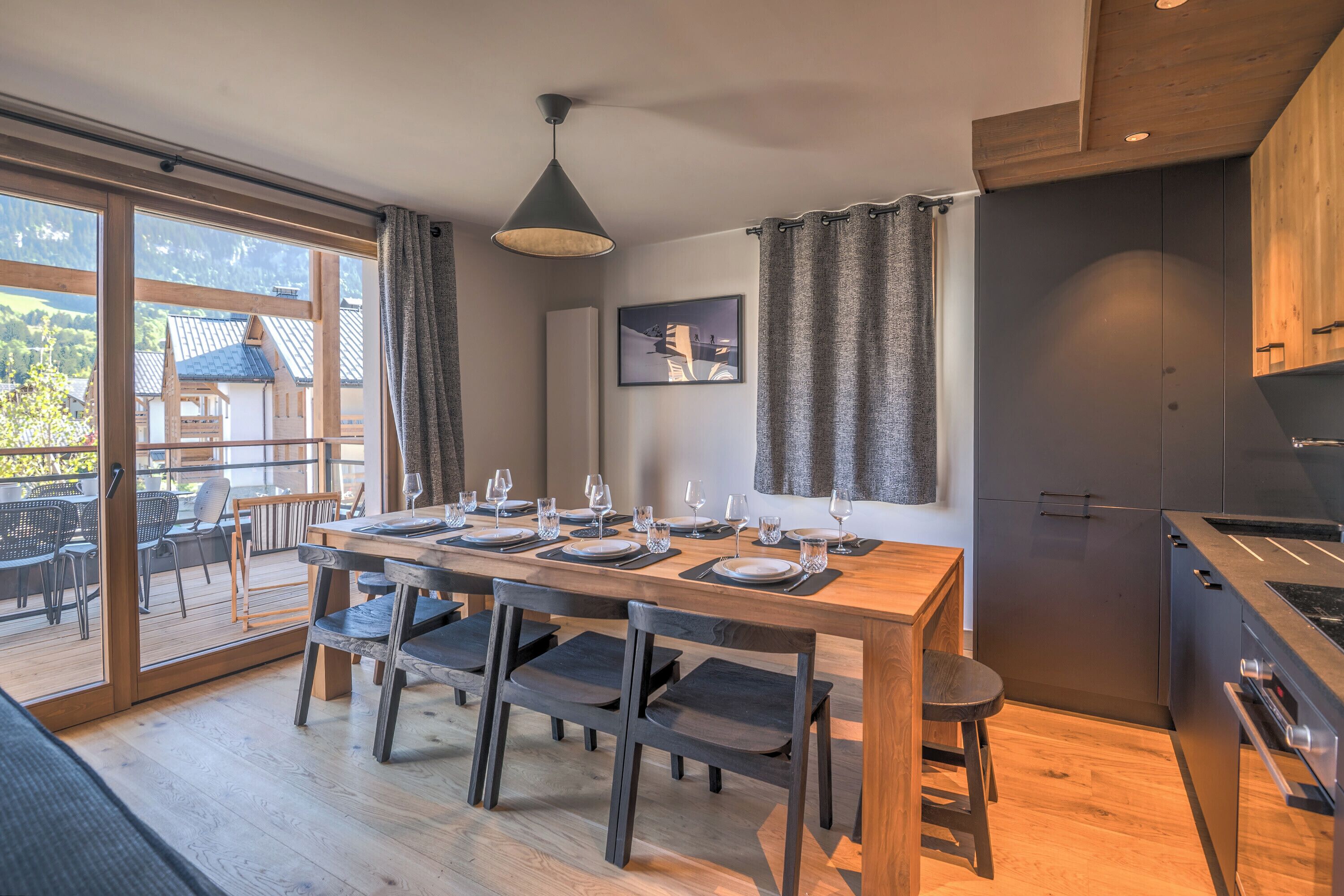 A modern kitchen with a built-in oven and a dining area with a wooden table and chairs.