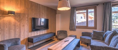 A modern living room with a wooden wall, a flat-screen TV, a sofa, a coffee table, and a bench.
