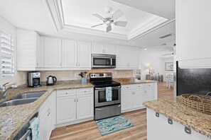 Una cocina moderna con gabinetes blancos, electrodomésticos de acero inoxidable y encimera de granito.