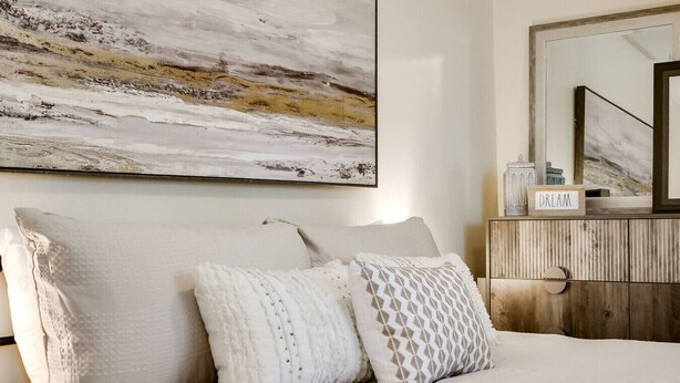A bedroom with a large abstract painting, a wooden dresser, and a mirror. - Charming Historic Retreat in Old Town St. Charles (Saint Charles)