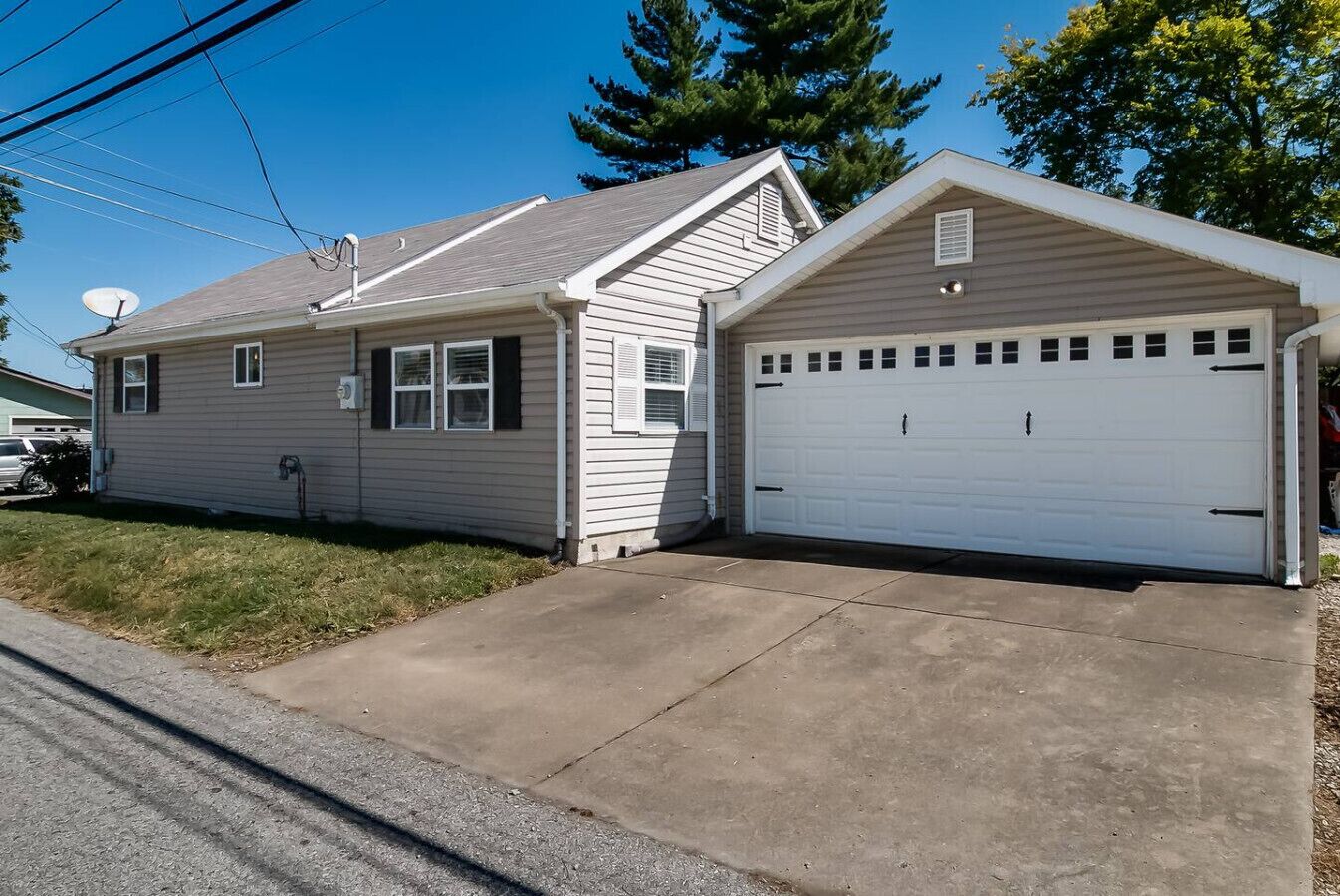 A single-story house with a garage, a satellite dish, and a well-maintained lawn.