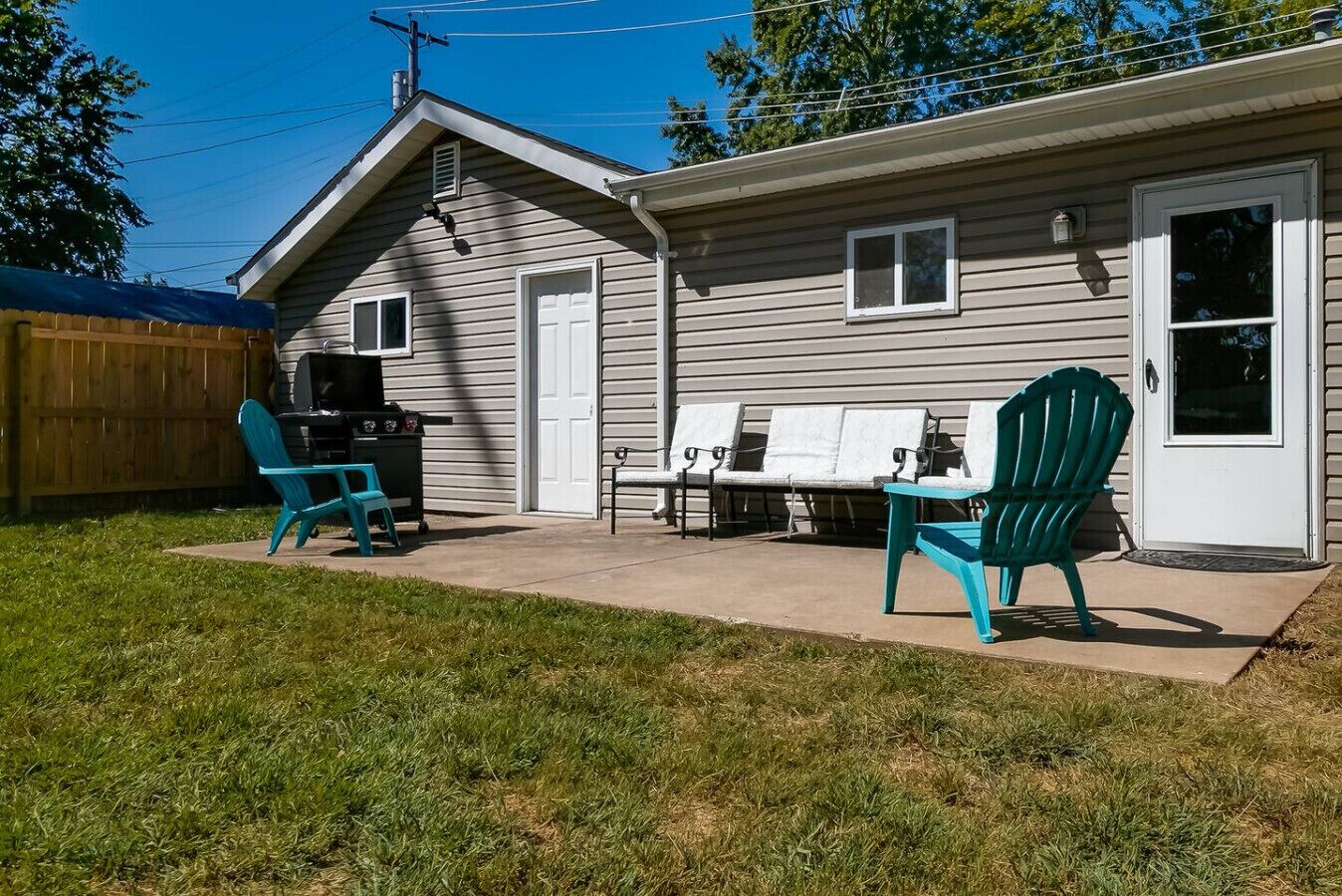 A house with a patio, a grill, and outdoor seating.