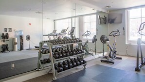 Un gimnasio con equipo de levantamiento de pesas, cintas de correr y bicicletas estáticas.