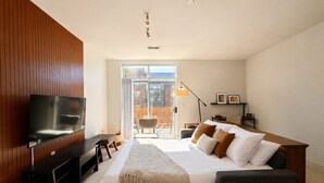 Un dormitorio moderno con televisión, cama, escritorio y una silla.