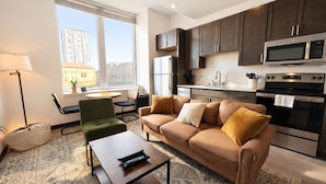 A modern living room with a sofa, coffee table, and a view of the city through large windows.
