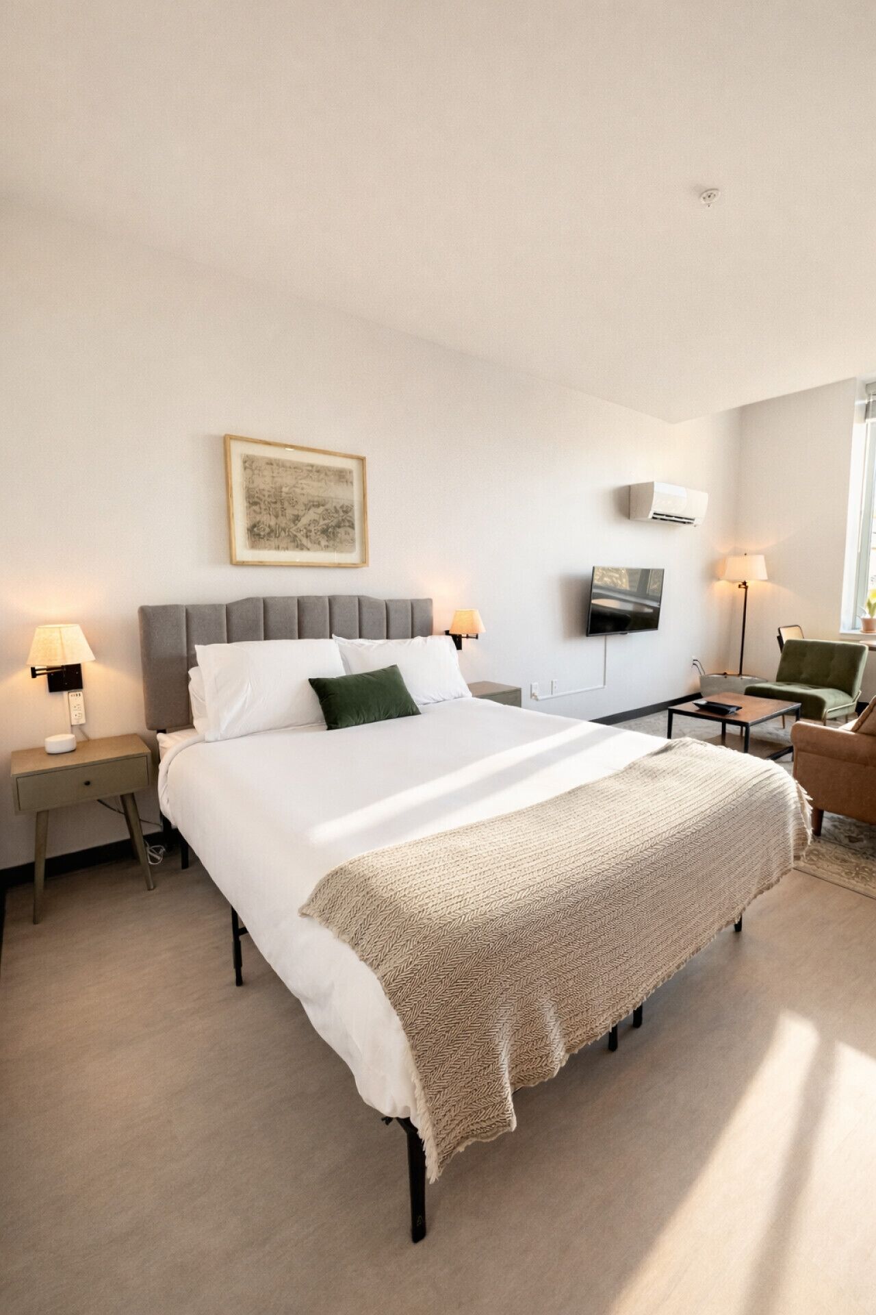 Een moderne hotelkamer met een groot bed, nachtkastjes, een flatscreen-tv en een raam.