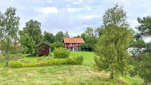 A large, red, two-story house with a red roof, surrounded by a well-maintained lawn and various trees. - 2 bedroom awesome home in Arboga (Arboga)