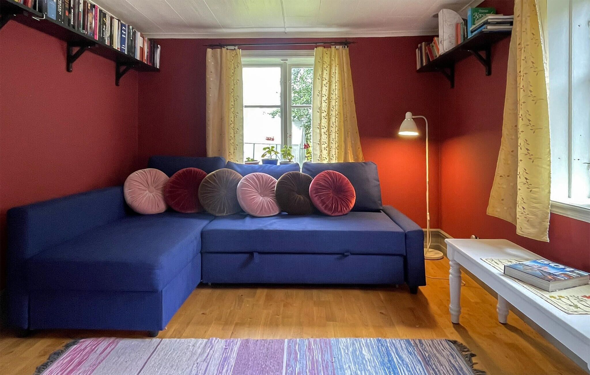 Ein gemütliches Wohnzimmer mit einem blauen Sofa, Holzboden und Bücherregalen.