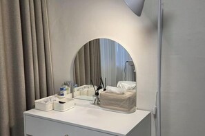 Une coiffeuse blanche avec un miroir, une boîte de mouchoirs et un petit panier.