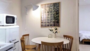 A compact kitchen with a microwave, a dining table with four chairs, and a decorative plant on the wall. - Stay Aurora (Seoul)