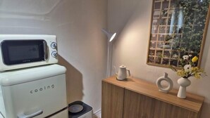 A kitchen with a white refrigerator, a microwave, and a wooden cabinet with a vase and a teapot on top. - Stay Aurora (Seoul)