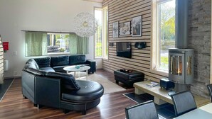 Un salon moderne avec un canapé d’angle, une table basse, une cheminée et un téléviseur fixé au mur.