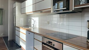 Une cuisine moderne avec des meubles blancs, un évier en acier inoxydable et un four encastré.