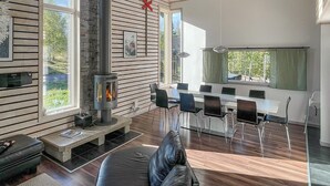 Un salon moderne doté d’une cheminée, de murs en bois et d’un coin repas avec des chaises et une table.