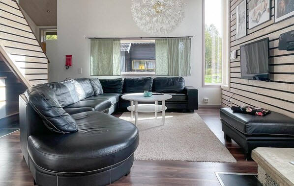 A modern living room with a sectional sofa, a round coffee table, and a TV mounted on the wall.