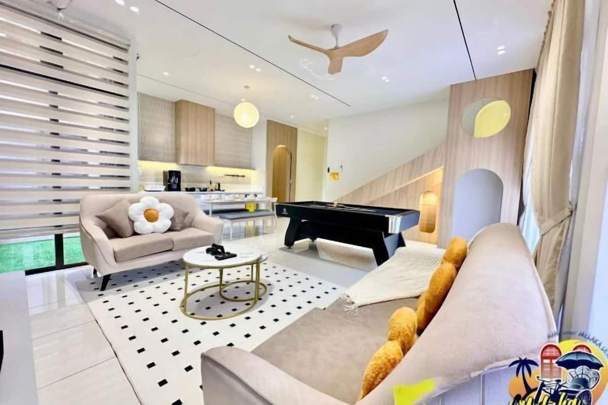 A modern living room with a sofa, coffee table, and a pool table.