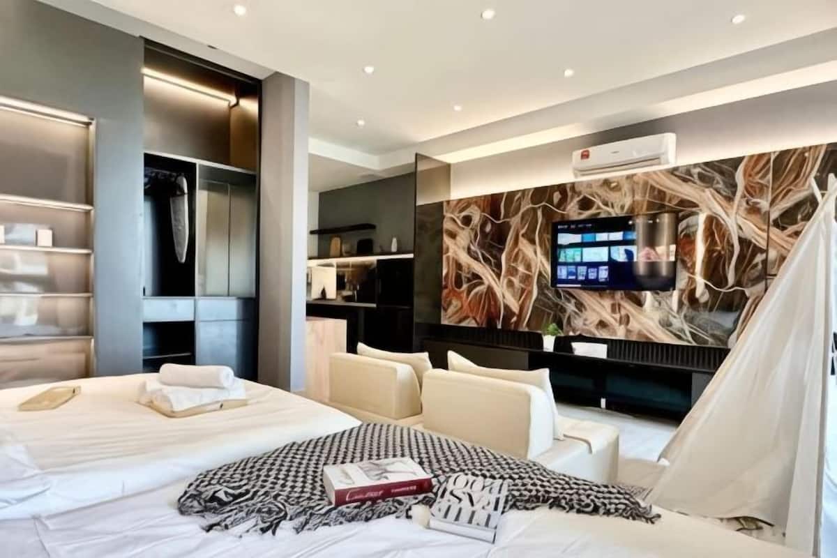A modern hotel room with a large bed, a TV, a wardrobe, and a wall-mounted artwork.