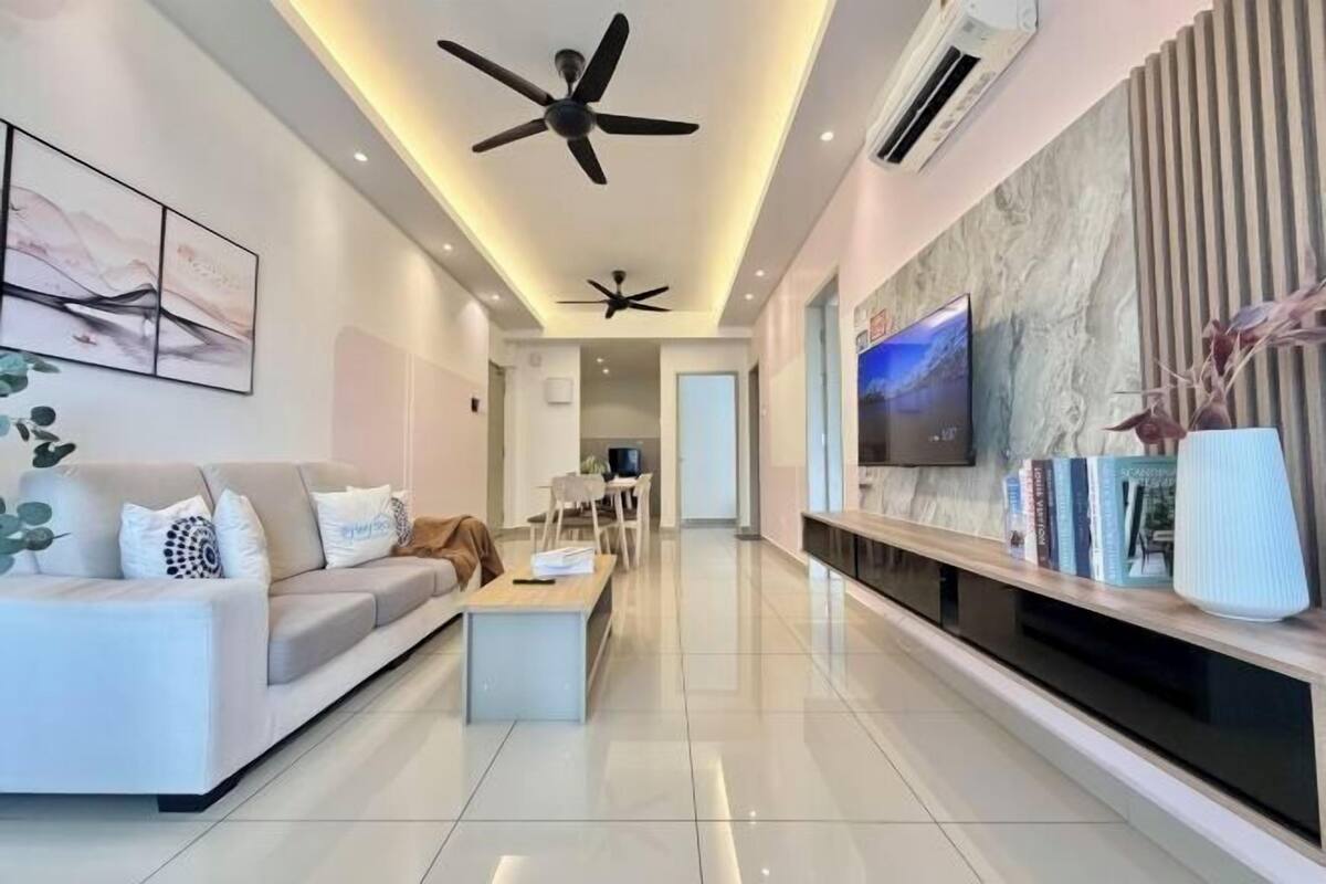 A modern living room with a sofa, coffee table, TV, ceiling fans, and a fireplace.