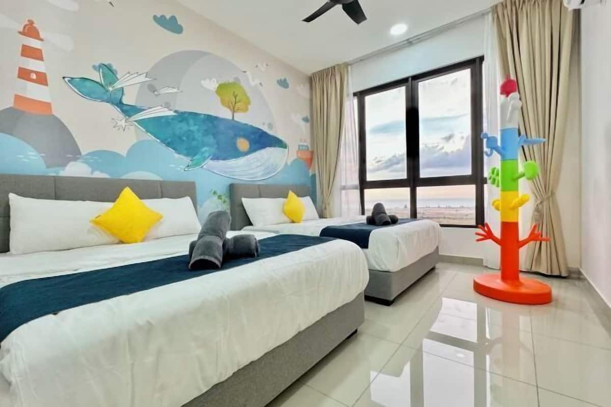 A hotel room with two beds, a mural on the wall, a large window, and a colorful toy in the corner.