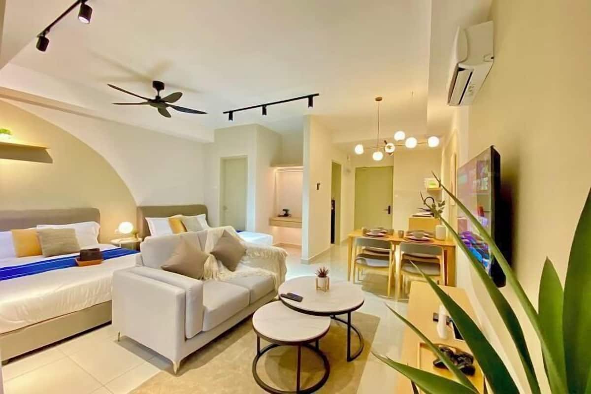 A modern hotel room with a bed, a sofa, a dining area, and a TV.