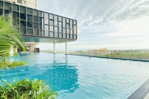 A swimming pool with a modern building structure above it, surrounded by greenery. - Bali Residence Melaka by Heystay Management (Melaka)