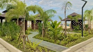 A resort with palm trees, a pathway, and small huts.