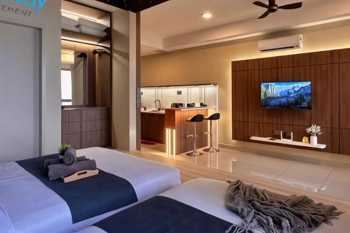 A hotel room with a bed, a TV, a kitchenette, and a ceiling fan.