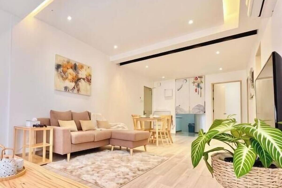 A modern living room with a sofa, coffee table, and a large plant.