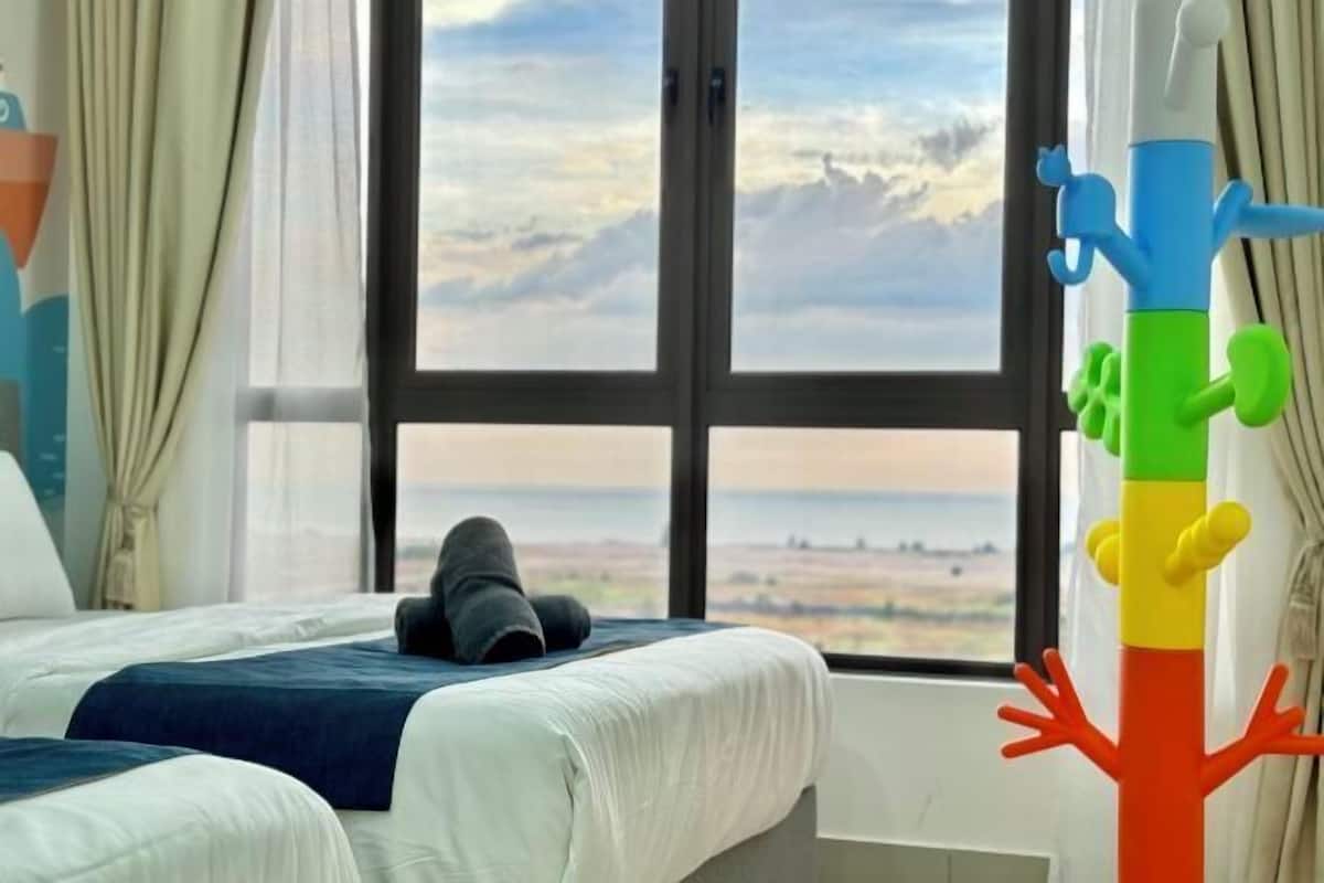 A hotel room with a large window, a bed, and a colorful abstract sculpture.