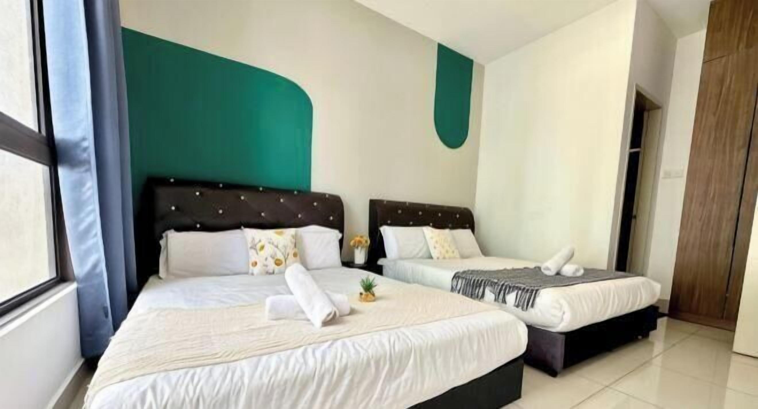 Une chambre d’hôtel avec deux lits, un mur d’accent de couleur turquoise et une grande fenêtre.