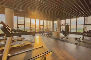 A gym with exercise equipment, large windows, and a view of the outdoors. - Bali Residence Melaka by Heystay Management (Melaka)