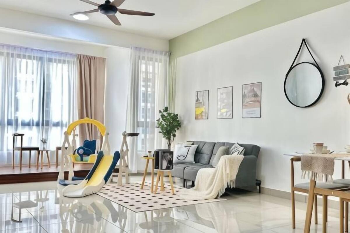 A modern living room with a sofa, a dining table, a ceiling fan, and a large window with curtains.