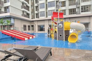 An indoor swimming pool with a slide, water play area, and lounge chairs. - Bali Residence Melaka by Heystay Management (Melaka)