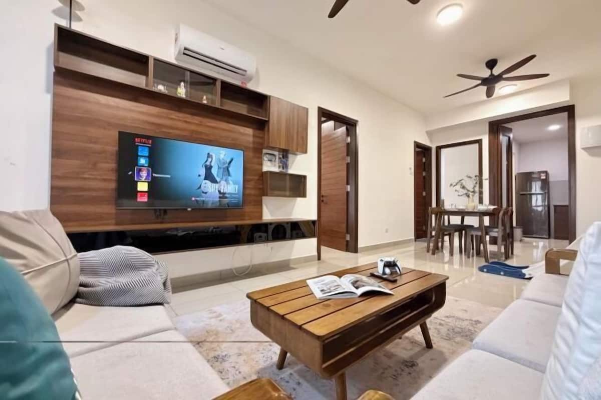 A modern living room with a flat-screen TV, wooden coffee table, and a sofa.