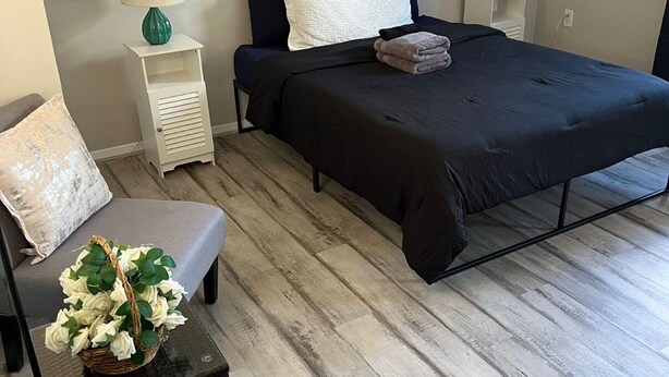 A bedroom with a bed, bedside tables with lamps, a chair, a small table with a basket of flowers, and a wall art of a car. - 3-bedroom townhome in delightful Germantown with AC without basement (Germantown)