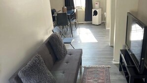A living room with a sofa, a TV, and a dining area in the background. - 3-bedroom townhome in delightful Germantown with AC without basement (Germantown)