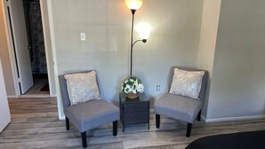 A room with two grey armchairs, a small table with a lamp, and a bed in the foreground. - 3-bedroom townhome in delightful Germantown with AC without basement (Germantown)