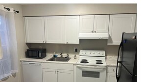 A compact kitchen with white cabinets, a microwave, a stove, and a refrigerator. - 3-bedroom townhome in delightful Germantown with AC without basement (Germantown)